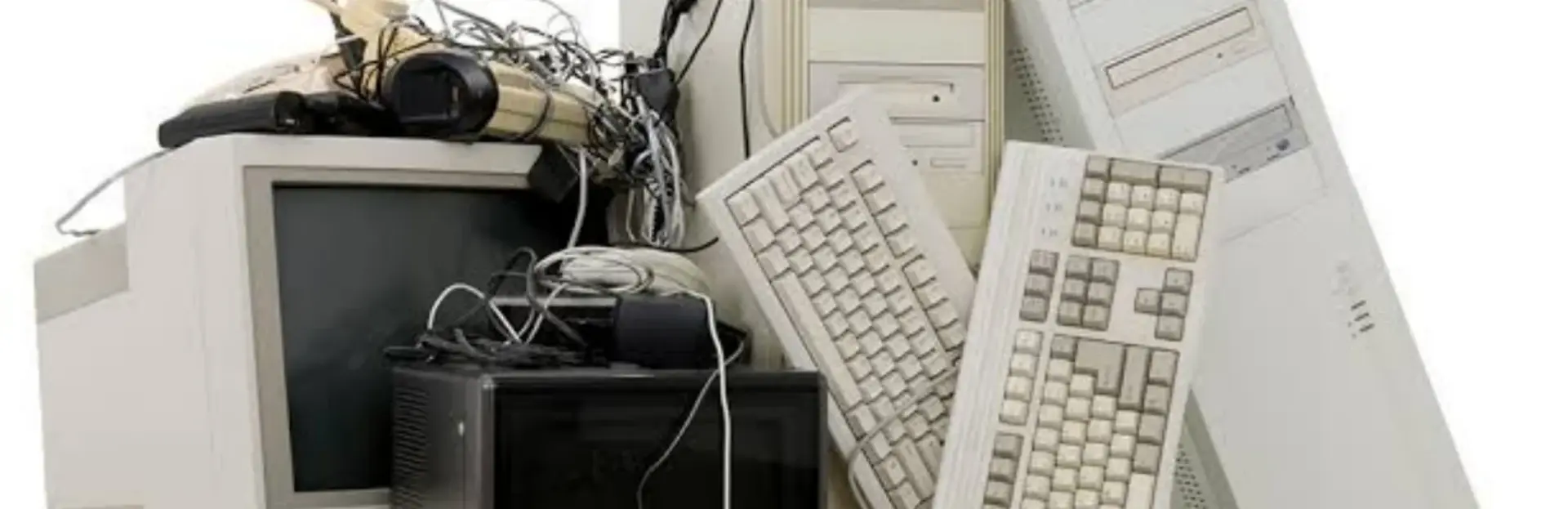 A pile of old desktop computers, monitors and keyboards awaiting refurbishment.