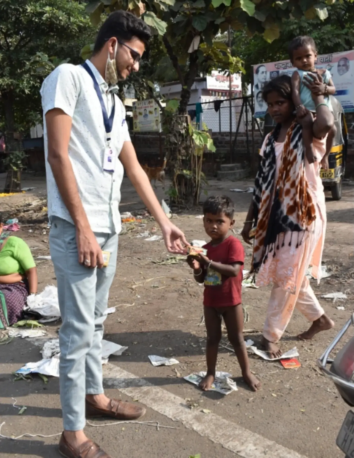A ReadoBook volunteer handing a book to a child standing on a roadside.