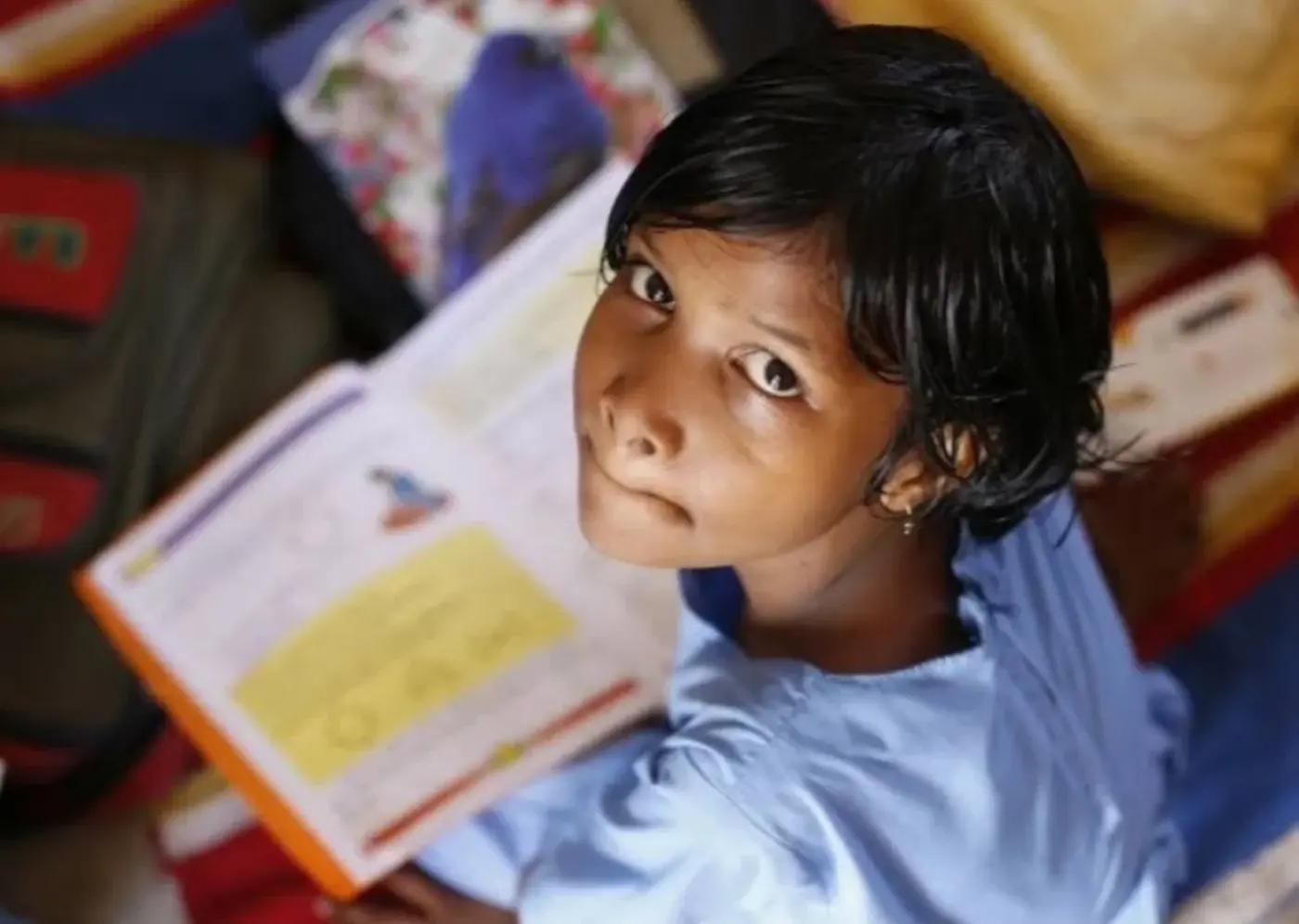 A girl looking up from the open book she is reading.
